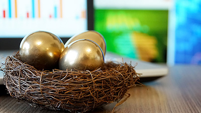 three golden eggs resting in a nest on top of a desk with a laptop screen in the background