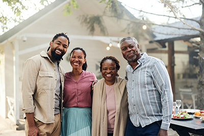 Happy African American mature couple and their adult children standing in the backyard and looking at camera.