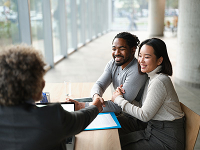 Happy diverse couple came to a successful deal with their insurance agent during a meeting in the office.