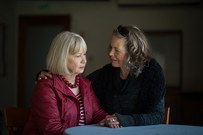 A senior lady supporting her friend by listening after receiving news by holding hands.