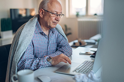 Photo of senior man works on a lap top at home